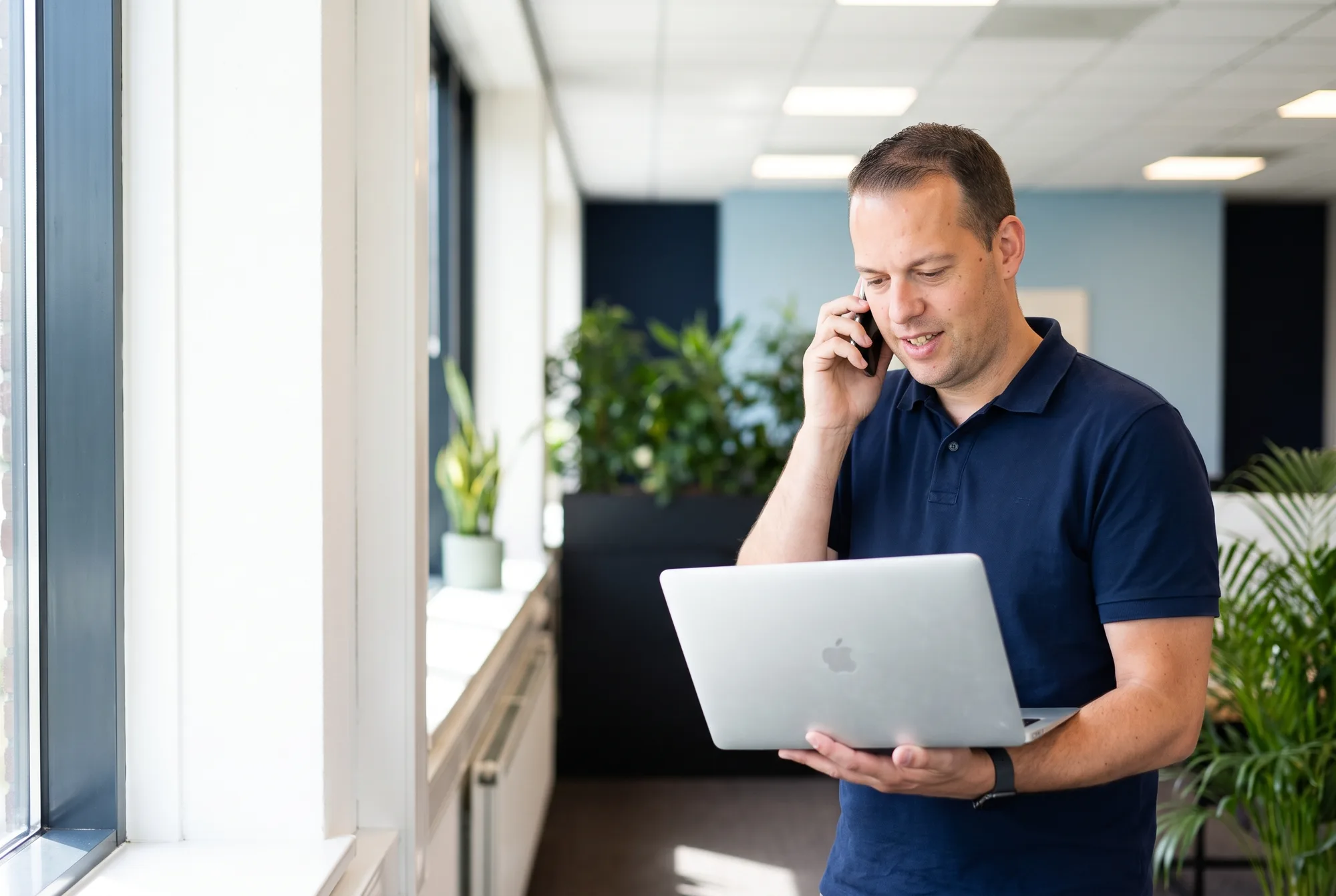 Jordy van Boutio helpt een klant telefonisch, met zijn laptop in de hand
