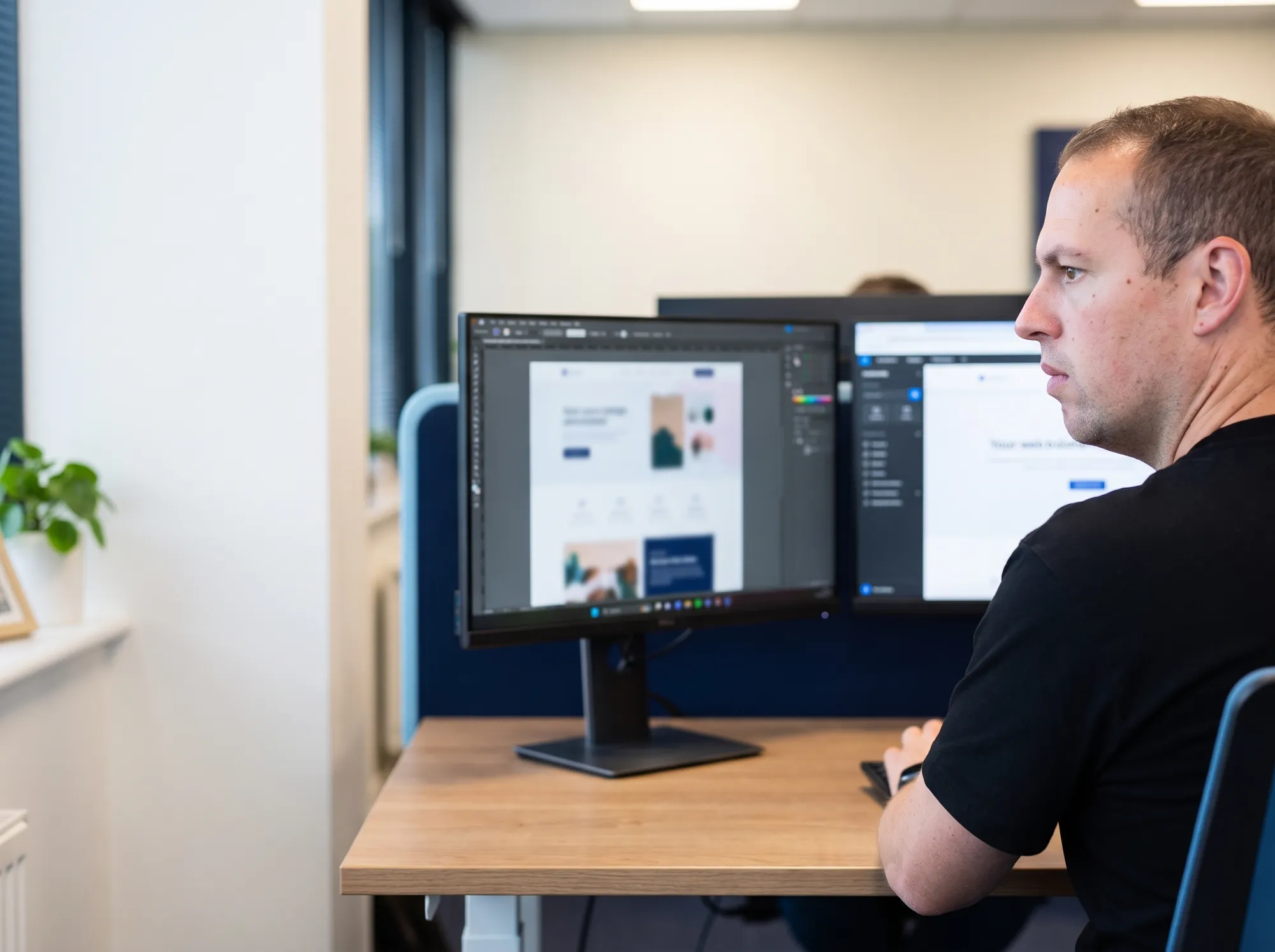 Jordy van Boutio bouwt geconcentreerd aan een website, met het design op het scherm ernaast