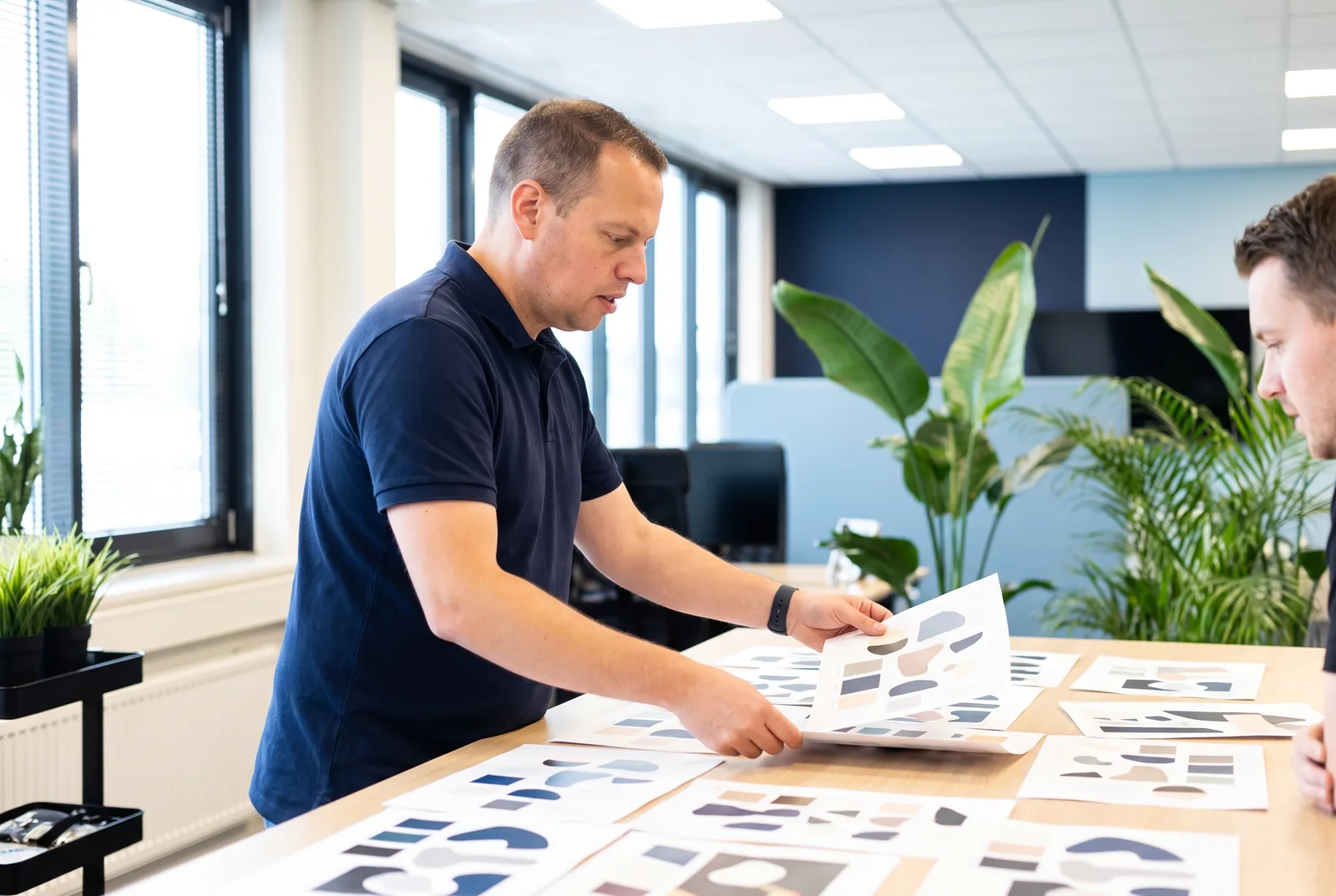 Jordy van Boutio legt huisstijlvellen met kleuren en vormen naast elkaar op tafel